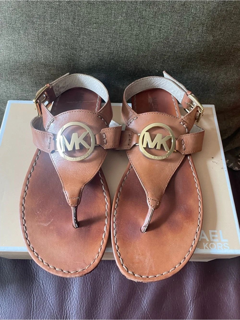 Michael Kors tan leather thong sandals feature a polished gold-tone MK log